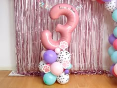 balloons and streamers in front of a pink backdrop with the number 9 on it