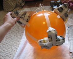 an orange ballon with tape wrapped around it being held by someone's hand