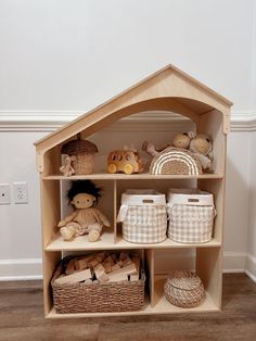 a wooden doll house shelf with baskets and stuffed animals