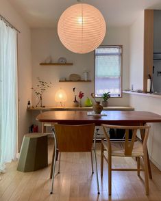 a dining room table with two chairs and a light hanging from the ceiling above it