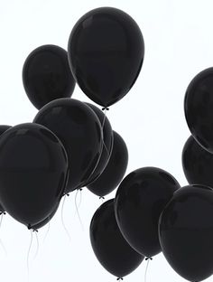 several black balloons floating in the air