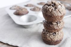 three chocolate muffins stacked on top of each other in front of a muffin tin