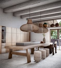 a dining room table and stools with lights hanging from the ceiling above it, in front of an open patio door