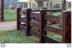 a wooden fence in front of a yellow house with grass and trees on the other side