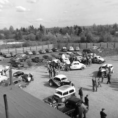 an old black and white photo of cars in a parking lot with people looking at them