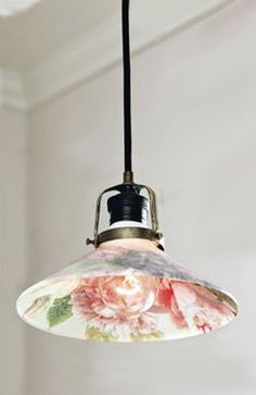 an old fashioned light hanging from a ceiling in a room with white walls and flowers on it