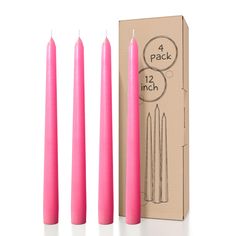 three pink candles sitting next to each other in front of a cardboard box with labels on it