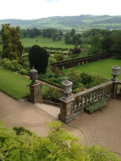 an aerial view of a garden with lots of greenery and stone pillars in the foreground