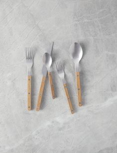 four forks and two spoons sitting next to each other on top of a table