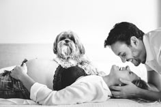 a man and woman laying on a bed with a dog