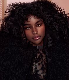 a close up of a person wearing a black jacket with curly hair and eye makeup