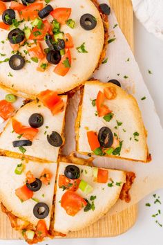 slices of pizza with olives, peppers and cheese on a cutting board next to a napkin