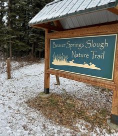 a sign for beaver springs slough nature trail in the wintertime with snow on the ground