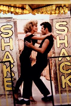 a man and woman are dancing in front of a stage with signs on it that say speak back