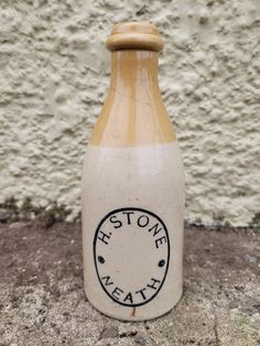 a stone bottle sitting on the ground next to a wall