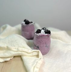 two glasses filled with blueberry chia pudding on top of a white table cloth