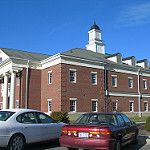 two cars parked in front of a building with a clock tower on it's side