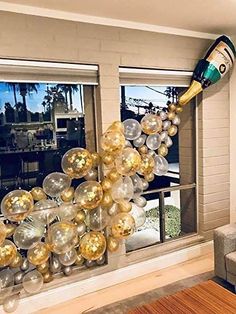 the balloon arch is decorated with gold, silver and white balloons in front of a window