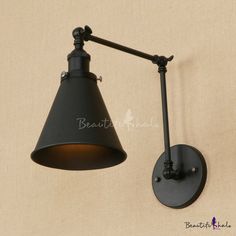 a black wall light with an arm and shade on the side, against a beige background