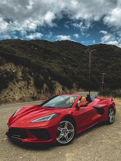 a red sports car is parked on the side of the road in front of mountains