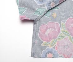 a close up of a flowered shirt on a white surface with the fabric pulled back