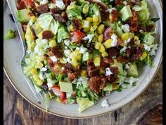 a salad with bacon, avocado, corn and feta cheese on it