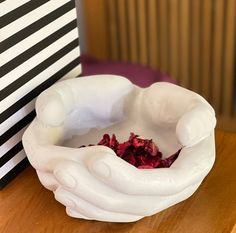 a white bowl filled with flowers on top of a wooden table