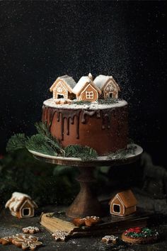 there is a cake with icing and houses on the top, surrounded by cookies