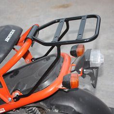 an orange and black motorcycle is parked on the street with it's seat up