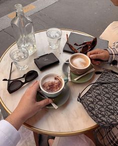 two people sitting at a table with cups of coffee