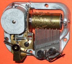 an old clock movement with metal parts on orange background