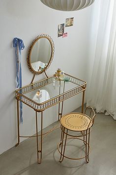 a vanity table with a mirror and stool in a white room next to a window