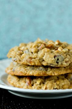 three oatmeal cookies on a white plate with a blue wall in the background