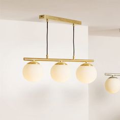 three lights are hanging from the ceiling in a room with white walls and flooring