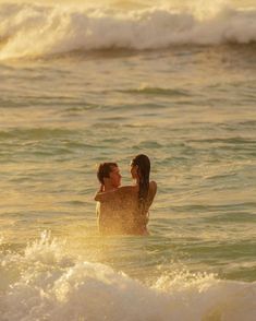 two people are in the ocean with waves coming up behind them and one person is holding his arm around the other