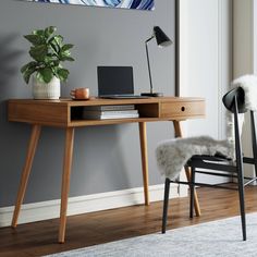 a desk with a laptop on it and a chair next to it in a room