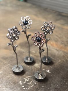 three metal flower sculptures sitting on top of a wooden table