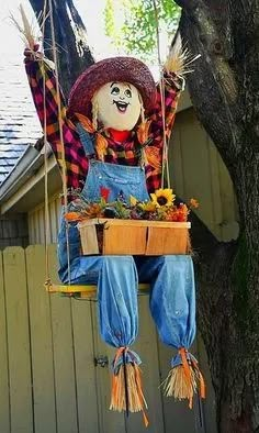 a scarecrow hanging from a tree in front of a house