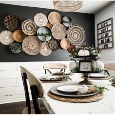 a dining room table set with plates and place settings on the wall above it is an arrangement of woven baskets