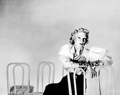 a woman sitting on top of a chair next to two metal chairs with legs crossed