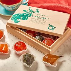 a box filled with different types of candies next to a cup of tea