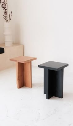 two small tables sitting next to each other on a white floor in front of a wall