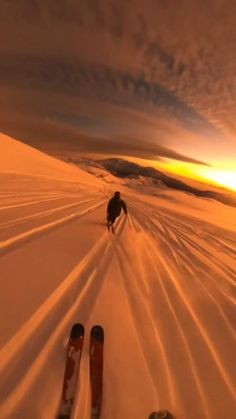 two skis are sitting in the snow as the sun goes down behind them,