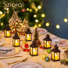 a table topped with lots of plates covered in christmas decorations next to a lit candle