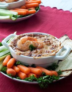 two bowls filled with dip, carrots and celery on top of a table