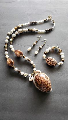 a necklace with seashells and pearls is shown on a gray surface, while the beads are beaded together