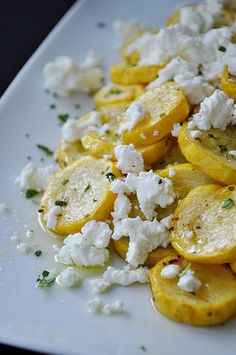 a white plate topped with sliced up lemons and feta cheese on top of it