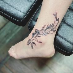 a woman's foot with a flower tattoo on her left leg and an arrow in the center