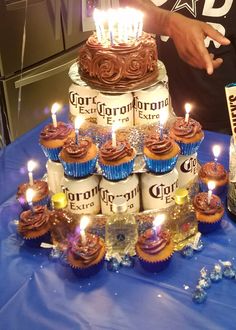 a man standing next to a cake with cupcakes on it and lit candles