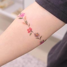 a woman's arm with flowers on it, and the word love written in pink ink